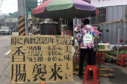 少年摊主卖的香肠，招牌很二次元，摊主穿得很夸张